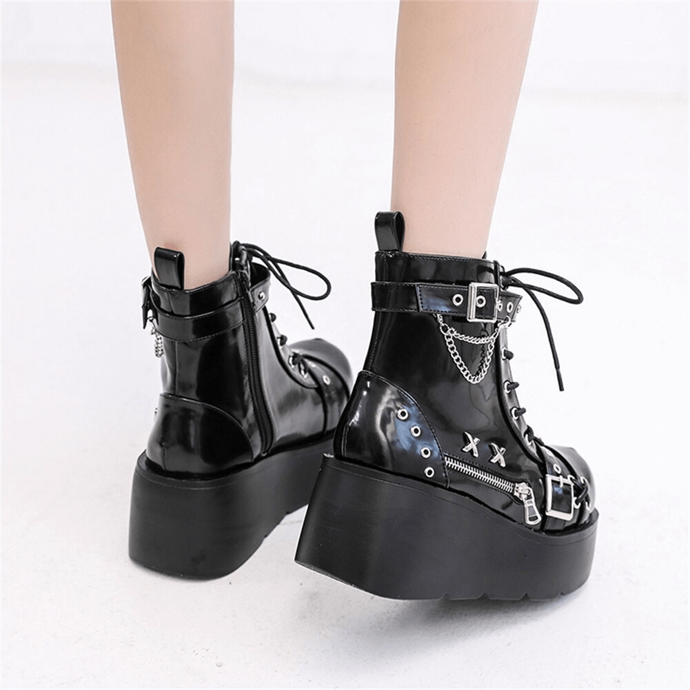 Styled shot of black gothic platform ankle boots on model - side angle showing punk hardware and leather finish