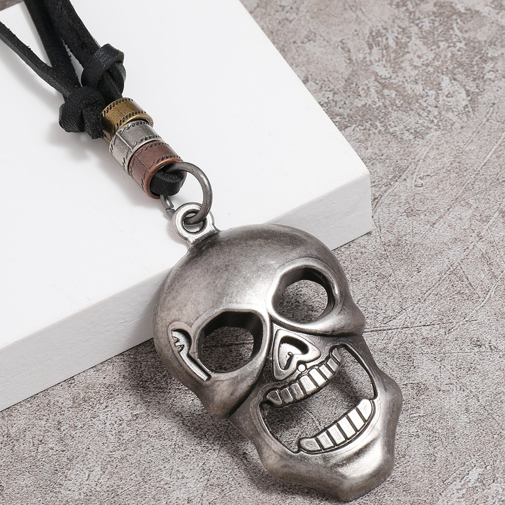 Side close-up of antique skull pendant necklace with clear facial bone structure, mixed metal beads, and leather cord
