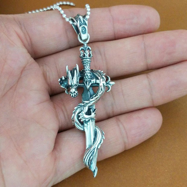 Dragon sword pendant clasp bail detail - left oblique view held in hand showing medieval sword hilt design