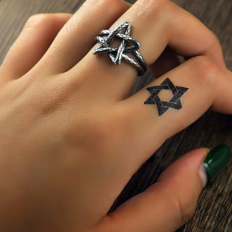 Pentagram ring styled on female hand with dark green nails and star tattoo, alternative gothic jewelry wear