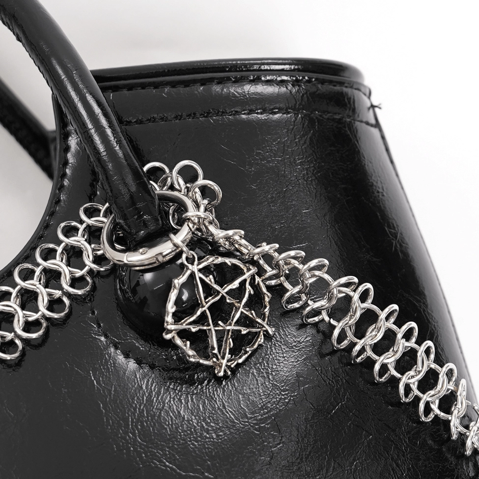 Alternative fashion black tote bag with skull ornaments and silver chain accents, styled product photography