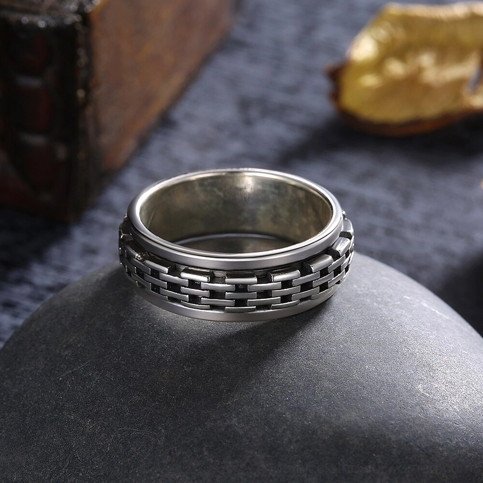 Antiqued sterling silver chain spinner biker ring front close-up with matte silver band edges and rotating gothic chain links on rustic dark stone background