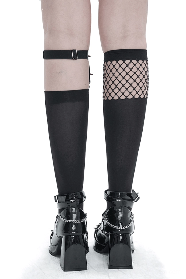 Mannequin legs displaying asymmetrical gothic knee-high socks with fishnet splice and metal heart buckle garter alongside platform boots