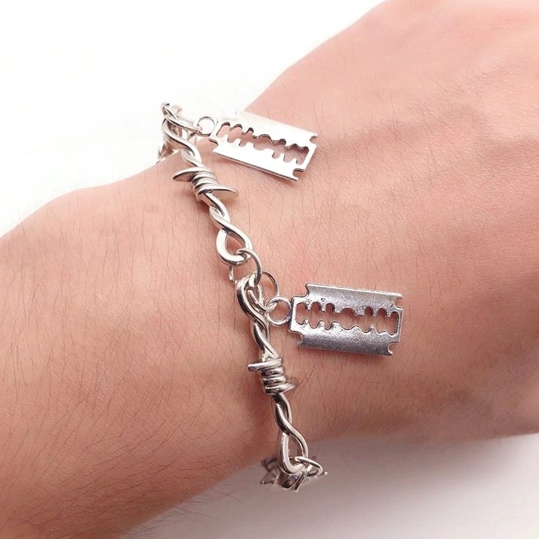 Barbed wire gothic bracelet on human wrist back side view, side oblique angle showing twisted metal chain and blade pendants