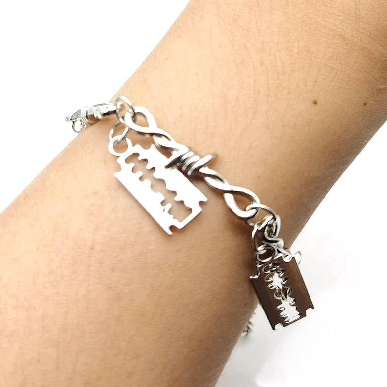 Close-up side view of barbed wire gothic bracelet showing detailed blade charm pendants and twisted barbed link chain design