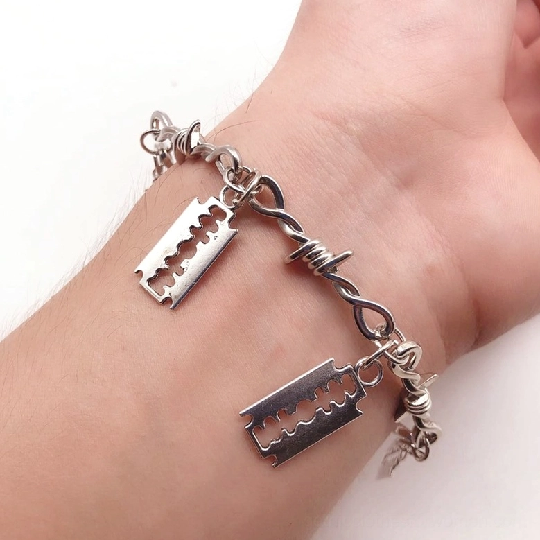 Gothic barbed wire blade bracelet top side view worn on human wrist, punk industrial style silver metal finish
