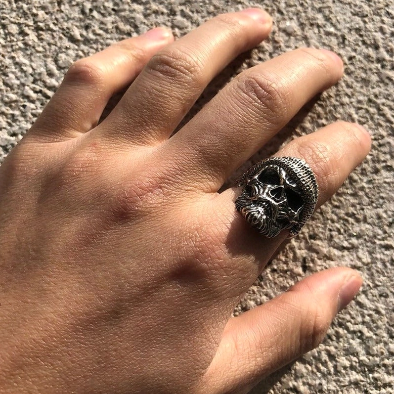 Bearded skull gothic ring worn on male right hand side view, detailed skull facial carving visible on concrete texture background demonstrating authentic wear