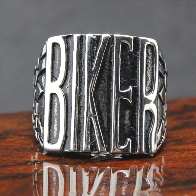 Gothic biker ring with detailed BIKER text, reflective wooden surface, vintage metal finish close-up