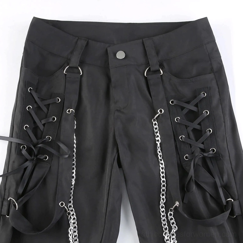 Close-up detail of black cargo pants waist area, featuring button fly, lace-up straps, metal chains and D-ring hardware