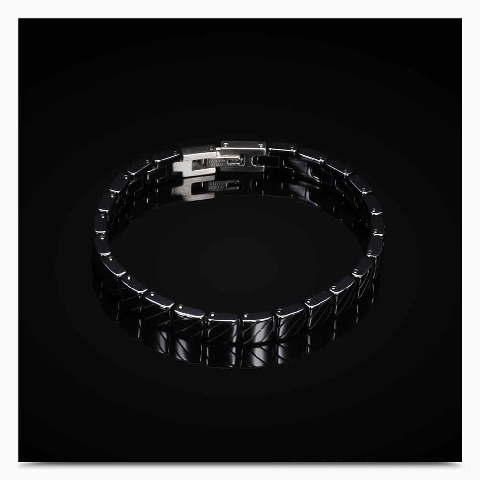 Black textured ceramic links and toggle clasp on glossy surface showing detail and craftsmanship