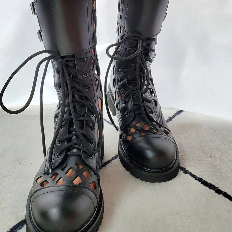 Black leather gothic combat boots on feet wearing styled outfit showcasing round toe cap and cutout vamp details
