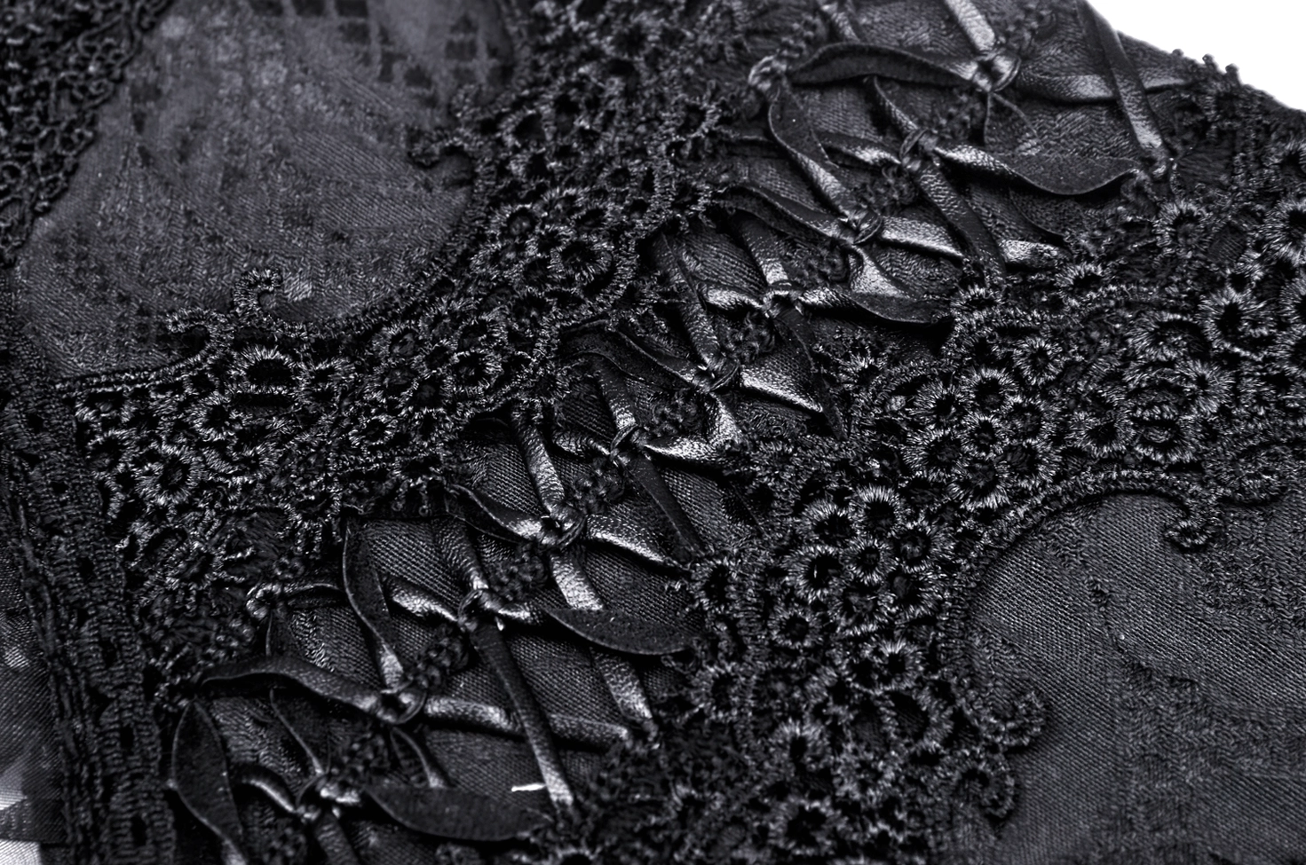 Macro close-up photography of black corset belt revealing intricate satin lace-up details and delicate floral embroidery craftsmanship
