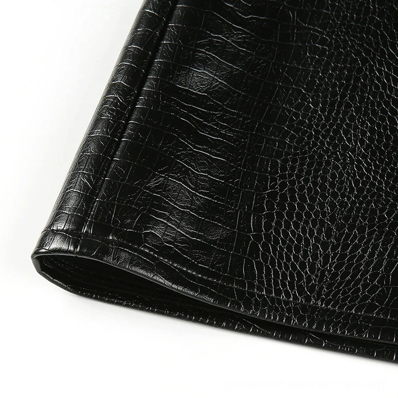 Close-up of black crocodile grain texture and folded hem edge on gothic mini skirt