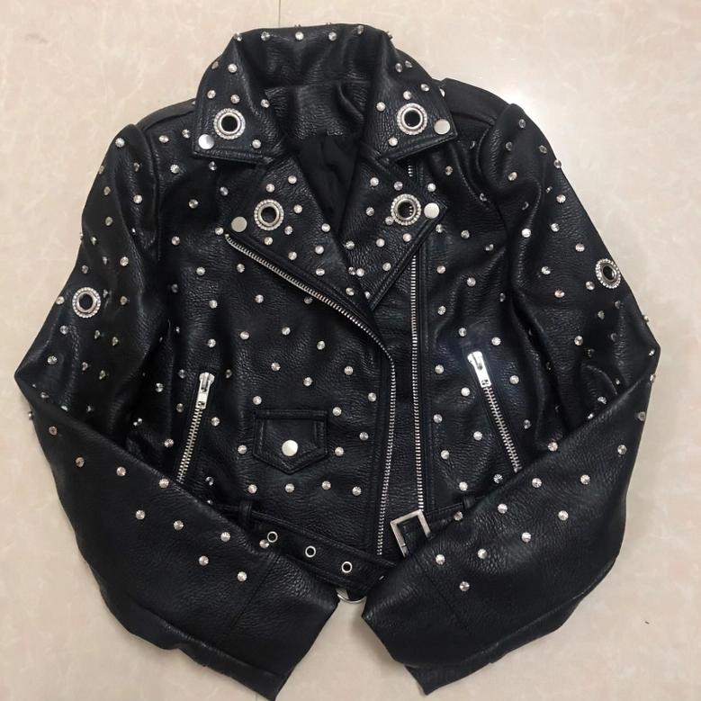 Black faux leather moto jacket front with asymmetrical metal zipper and waist belt on beige tile surface