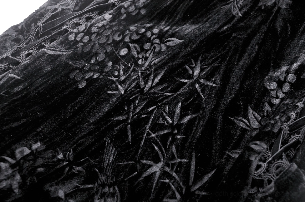 Black crushed velvet fabric texture close-up with embossed floral plant pattern and shiny velour finish
