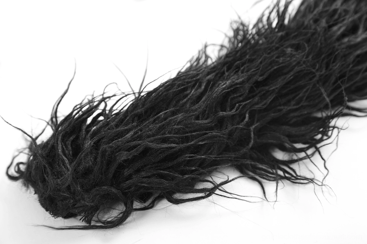Close-up side view of black faux fur hair extension end showing fluffy loose frayed fibers