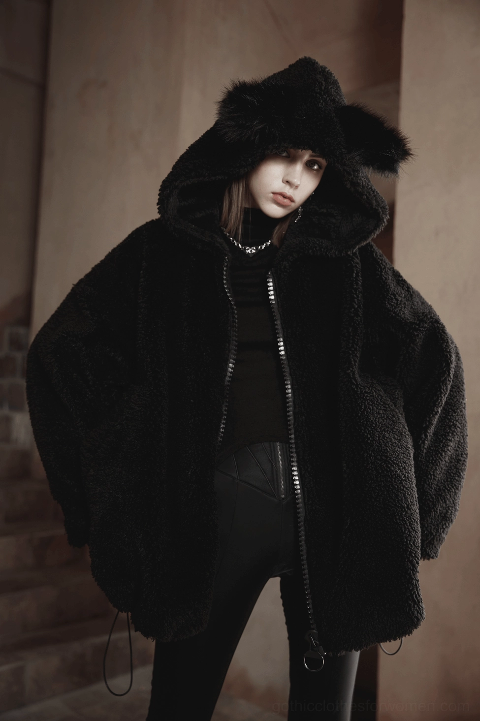 Black fox ear gothic hooded fleece jacket styled with dark outfit on model against brick wall, gothic aesthetic