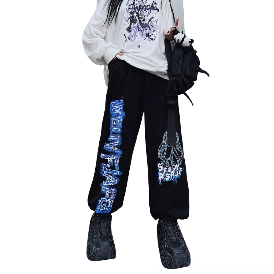 Black gothic wide leg anime print jogger pants styled with chunky sneakers and crossbody bag, full body front view