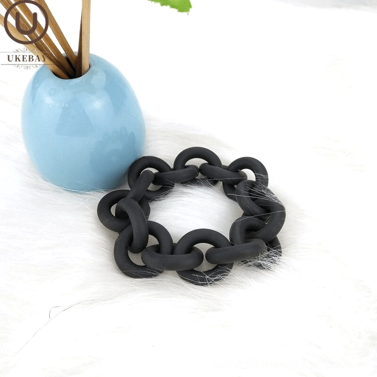 Handmade black rubber chain bangle paired with blue ceramic reed diffuser on faux fur background, aesthetic flat lay