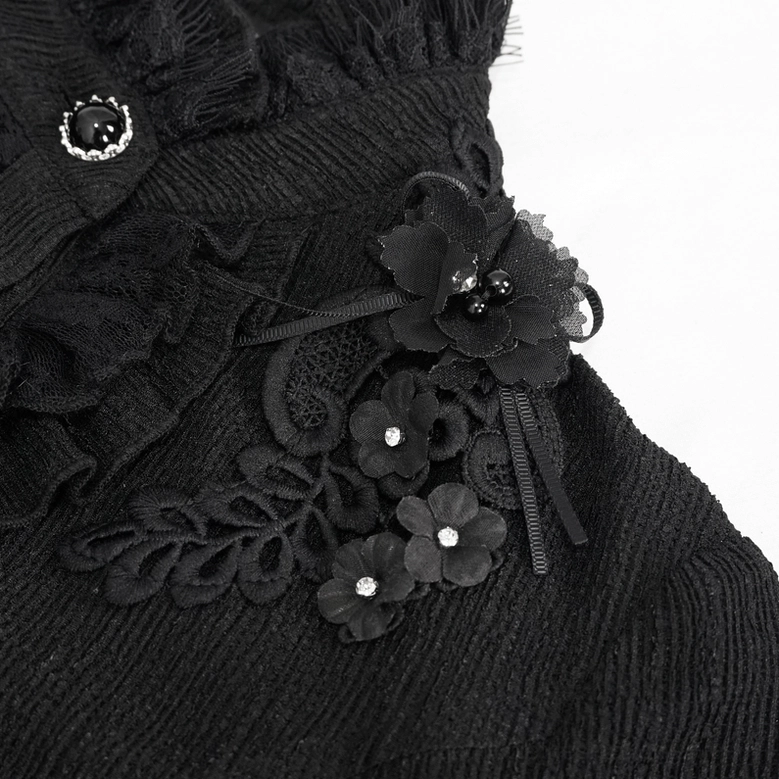 Macro close-up of black gothic blouse floral appliqué detail with ribbon trim and gem-encrusted button