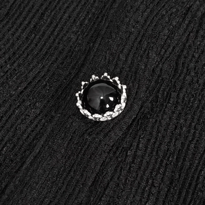 Close-up detail of gothic blouse button and ribbed textured knit fabric with silver-rimmed black gem button