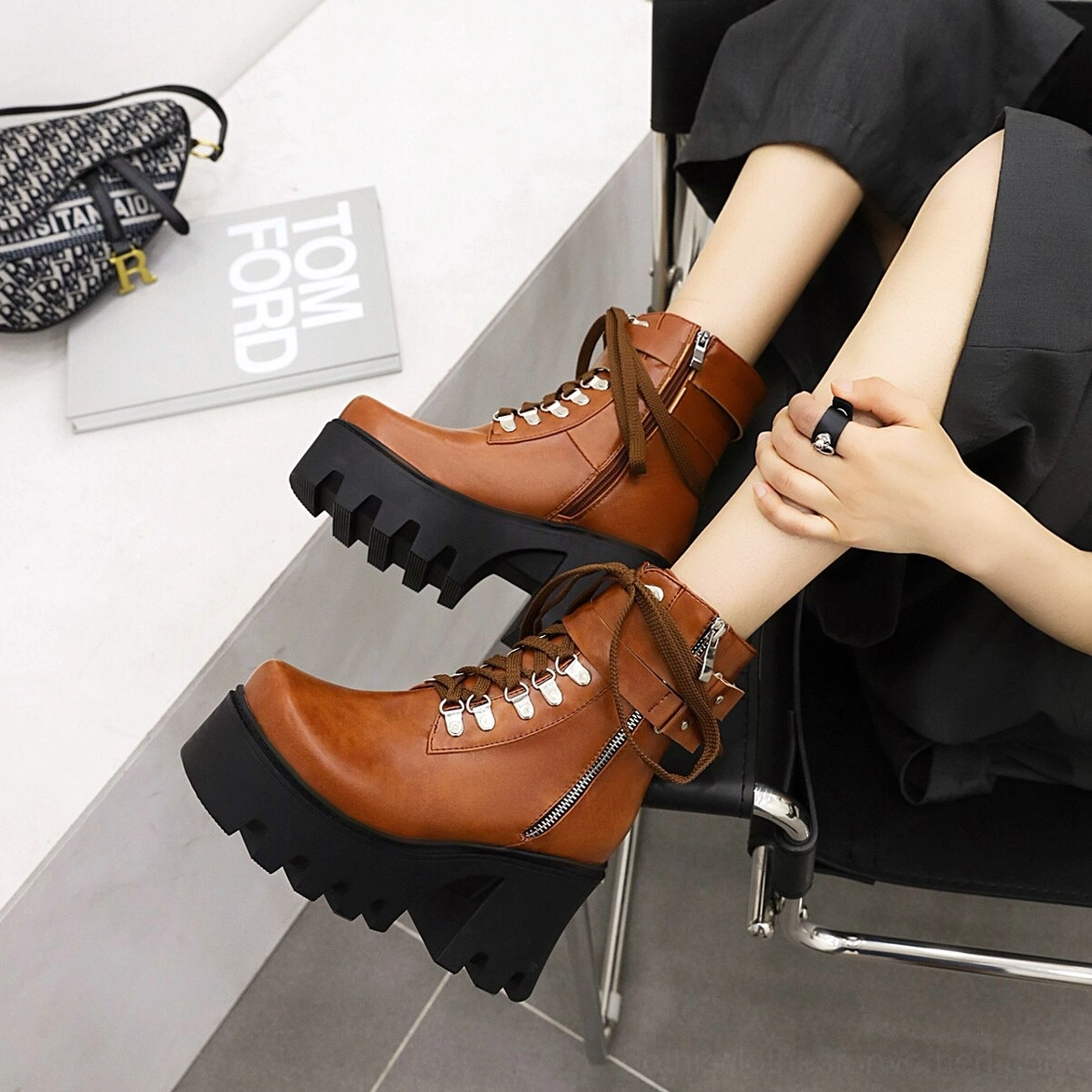 Black gothic platform combat boots showing round toe silhouette and decorative fretwork details, angle view of architectural design