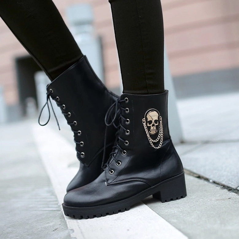 Woman wearing black gothic lace-up ankle boots with dark skinny jeans on outdoor paved sidewalk, demonstrating real-world wear and styling