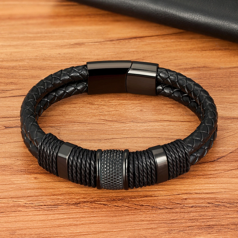 Black leather gothic bracelet flat lay on wooden surface featuring textured central magnetic clasp hardware