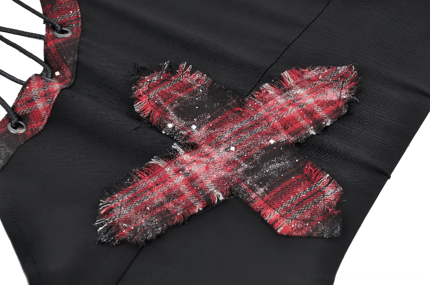 Close-up detail of distressed red plaid cross patch with frayed edges and glitter accents on black gothic corset cami