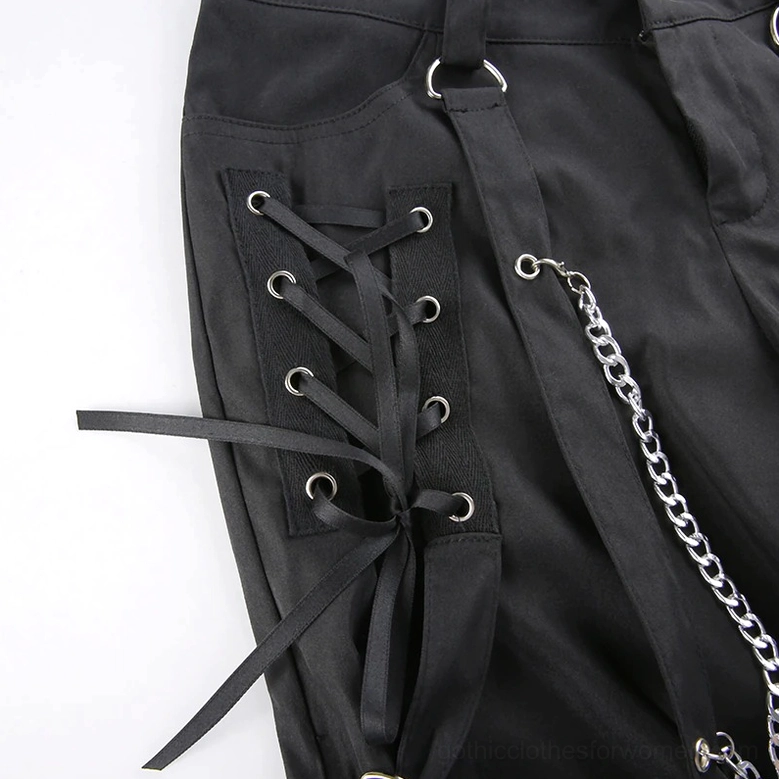 Side pocket close-up of black gothic cargo pants, showcasing black lace-up straps, decorative metal chain and metal hardware details