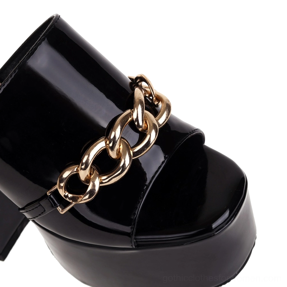 Close-up front view of black glossy patent leather gothic platform heel with prominent gold chain strap