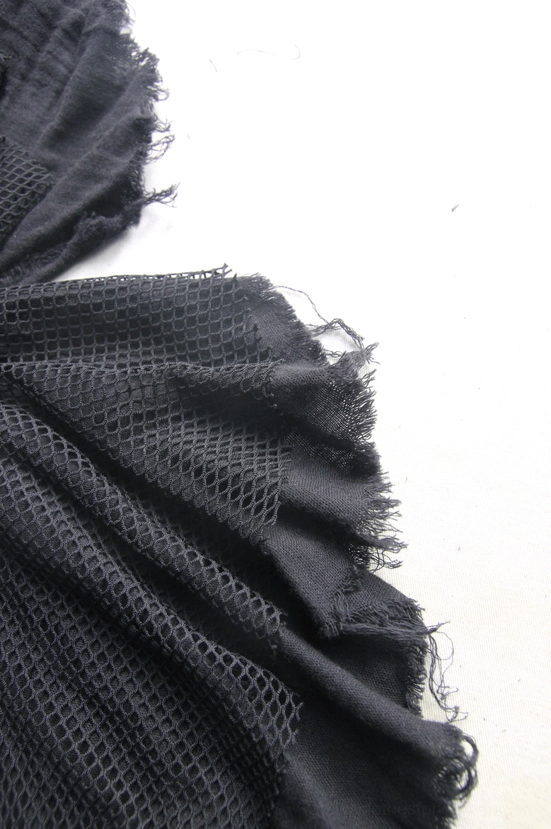 Fabric texture close-up of black gothic denim skirt - showing mesh and frayed cotton blend detail