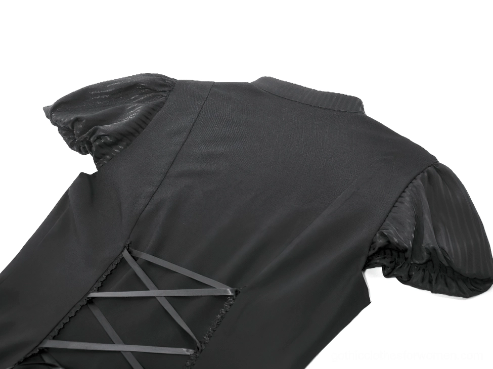 Close-up back detail of black gothic dress showing functional lace-up corset closure with matte black fabric and precise stitching on white background