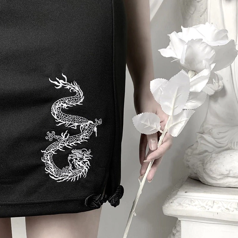 Close-up detail of dragon embroidery and frog button closure on black gothic mini dress hem