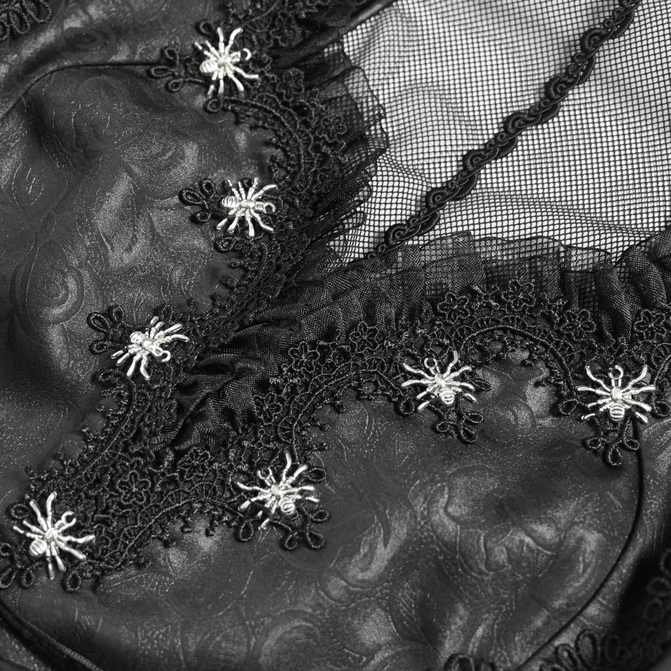 Close-up of black gothic dress fabric showing faux leather texture, spider embroidery, and lace trim