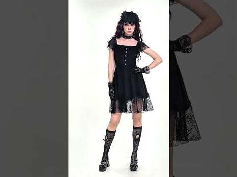 Black gothic mini dress styled with fishnet stockings on dark-haired model, front full-body studio shot