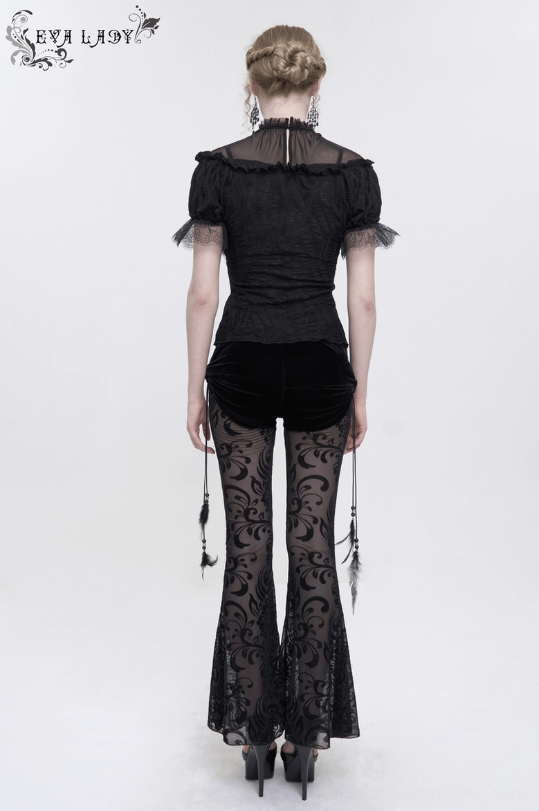 Full length view of black gothic flare pants with feather ornaments, showing overall proportions and drape