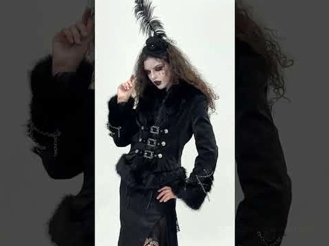 Black gothic faux fur jacket with chain trim on female model - three-quarter view with feather accessory