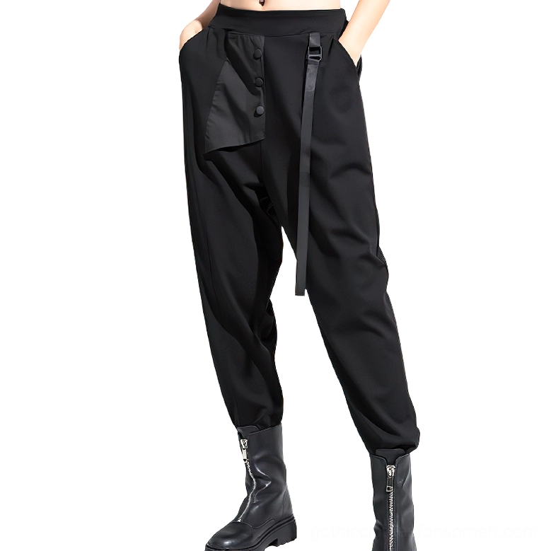 Front three-quarter view of black gothic women's harem trousers with model's hands in asymmetric buttoned pockets, showing side ribbon and elastic waistband