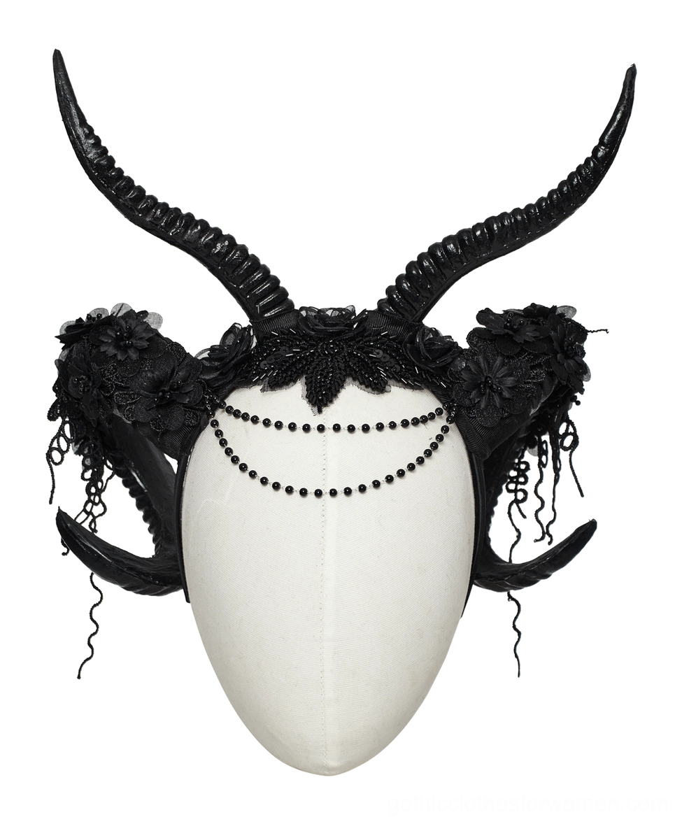 Black gothic horned headpiece on mannequin featuring curved ram horns, beaded chain, and floral lace decoration front angle