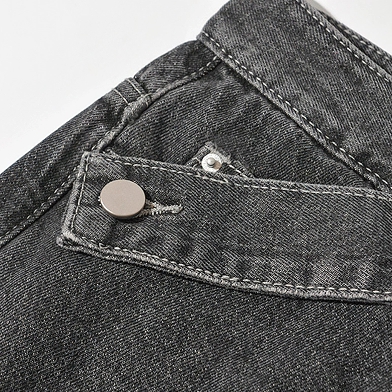 Black gothic denim jeans asymmetric waistband button and metal snap closure close-up detail shot