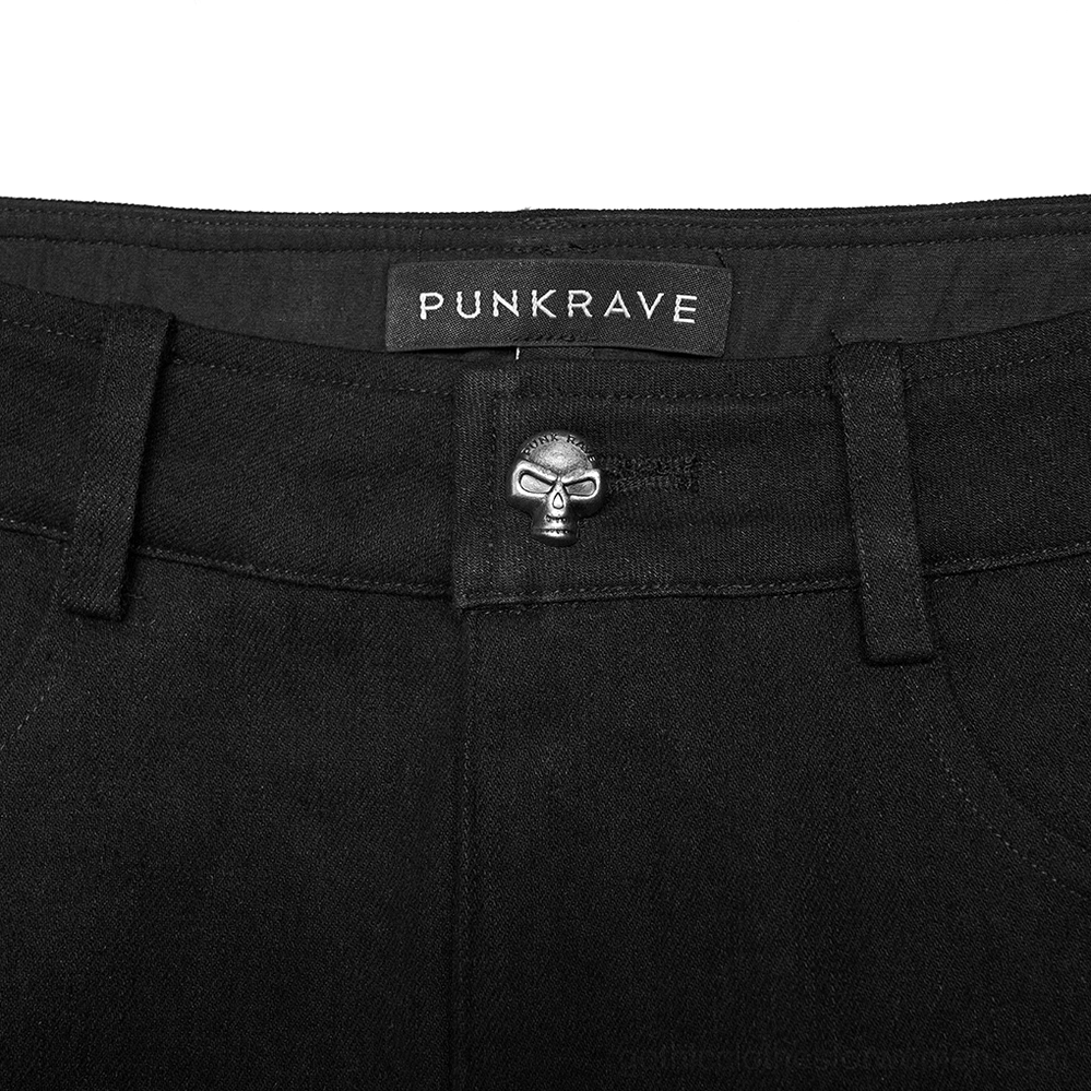 Close-up detail of black gothic jeans waistband featuring skull-shaped button and punk rave brand label on women's alternative denim