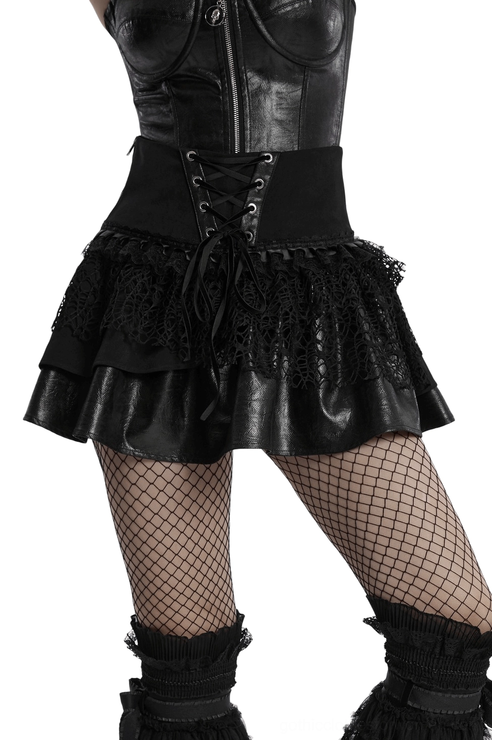 Black gothic lace-up mini skirt with layered mesh and faux leather detailing worn by model, front view showing metal eyelet lacing and ruffled hem