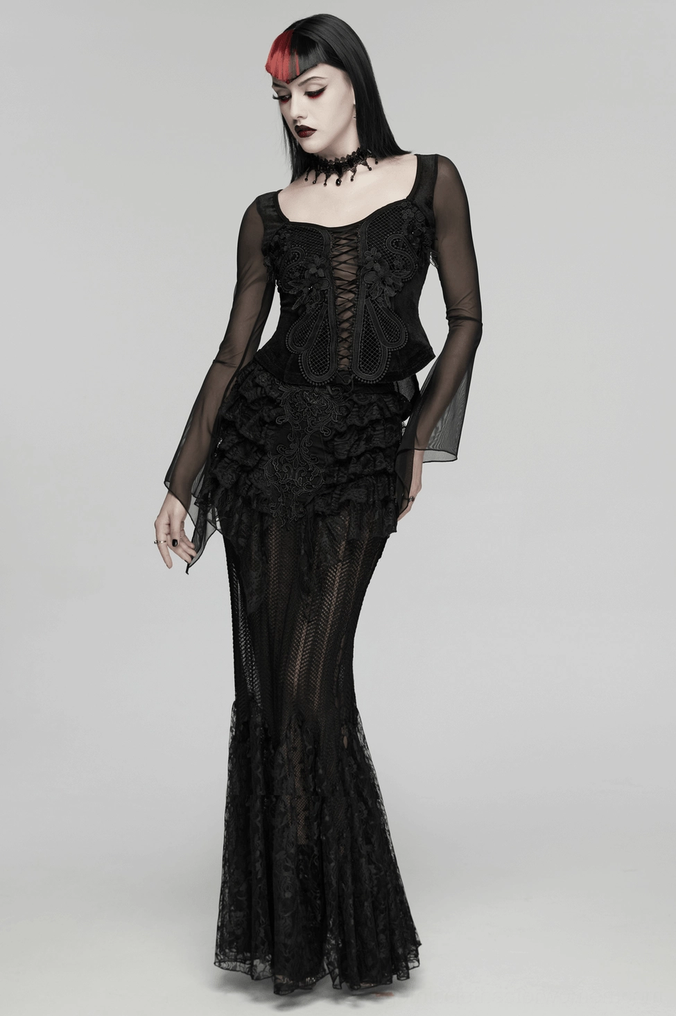 Three-quarter view of black gothic lace-up embroidery top on model with flowing sheer mesh sleeves