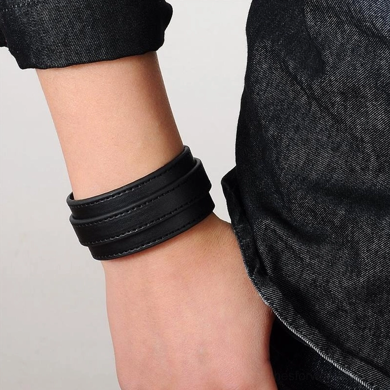 Black gothic leather wristband worn on model wrist, close-up side view showing fit and proportions with denim clothing