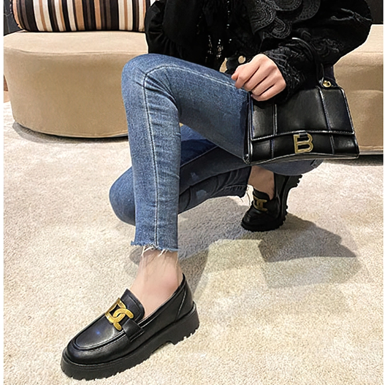 Female model wearing black gothic platform loafers with denim jeans in indoor carpeted space, low side angle shot showcasing how platform elevation elongates the leg and complements casual outfits