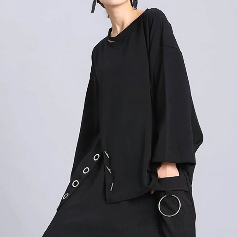 Black loose long sleeve gothic women's pullover top, three-quarter oblique front view showing asymmetric hem with slit, eyelets, and attached ring detail