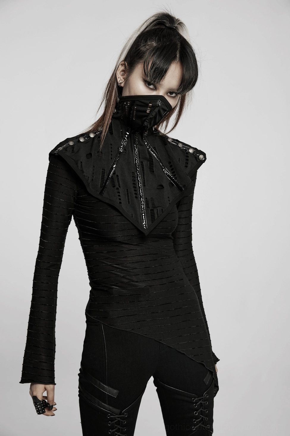 Model wearing complete black gothic outfit with mesh face mask collar and fitted long-sleeve top, three-quarter side view