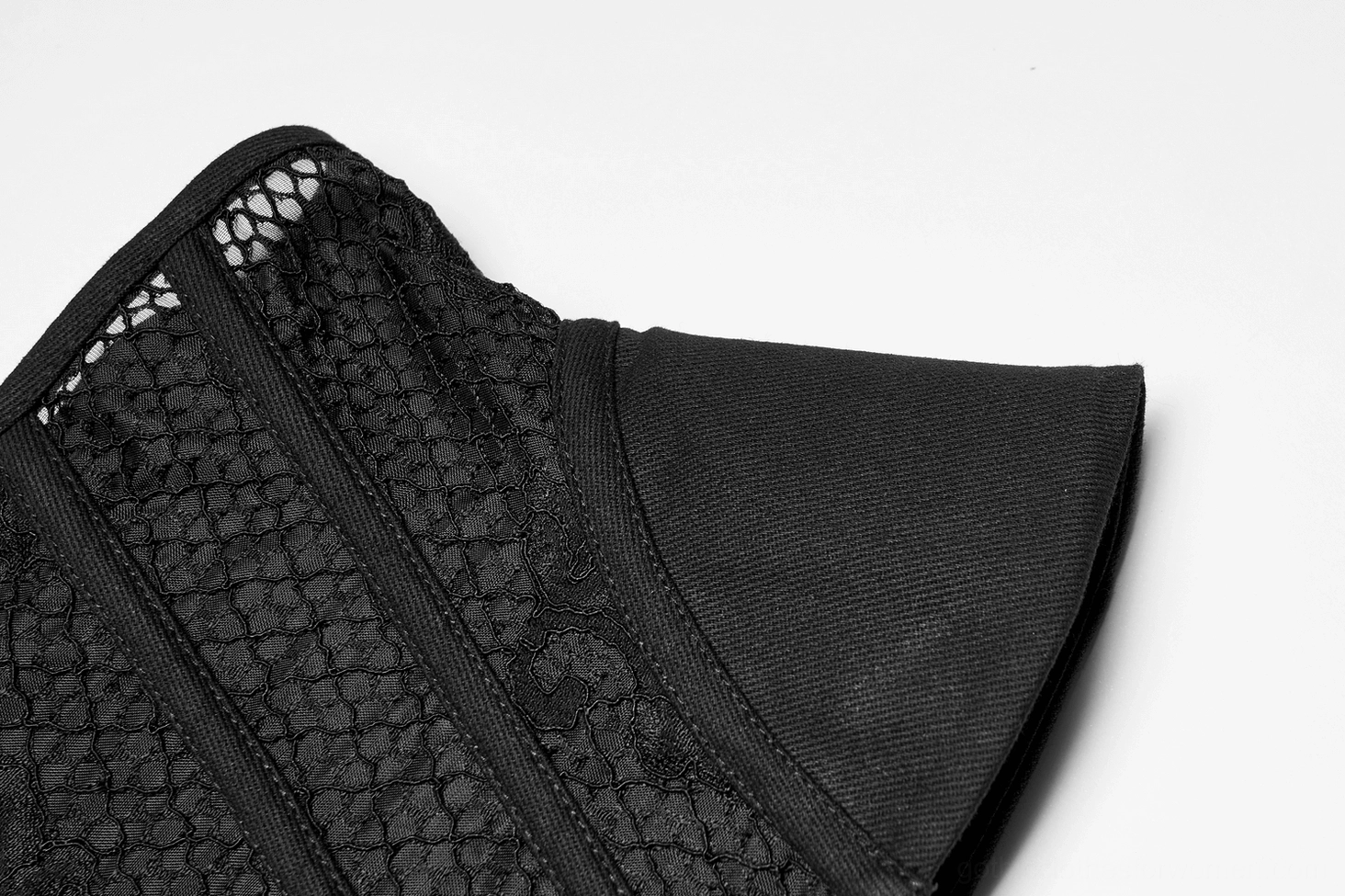 Close-up texture detail of black gothic cincher corset showing fishnet mesh fabric with floral embroidery and solid fabric trim on side