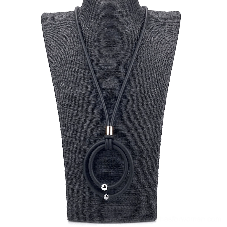 Close-up of black gothic pendant necklace on black jewelry bust displaying gold metal connector and round pendant details